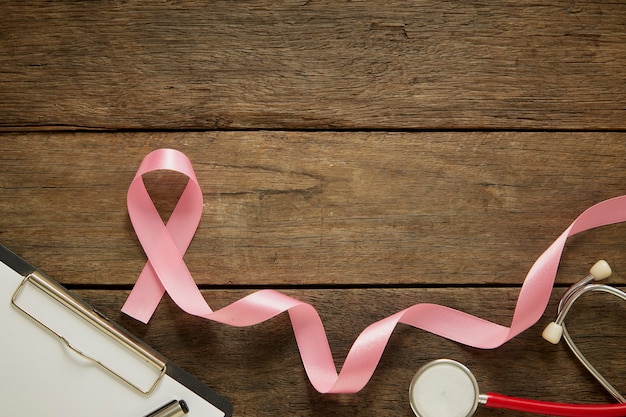 Pink ribbon on wooden breast cancer awareness background concept