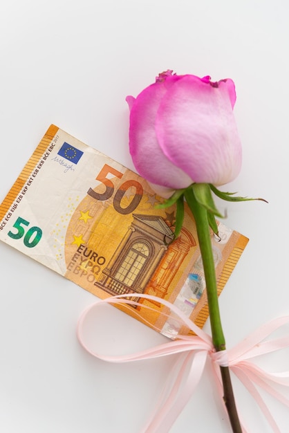 Una rosa rosa in regalo con una banconota in euro