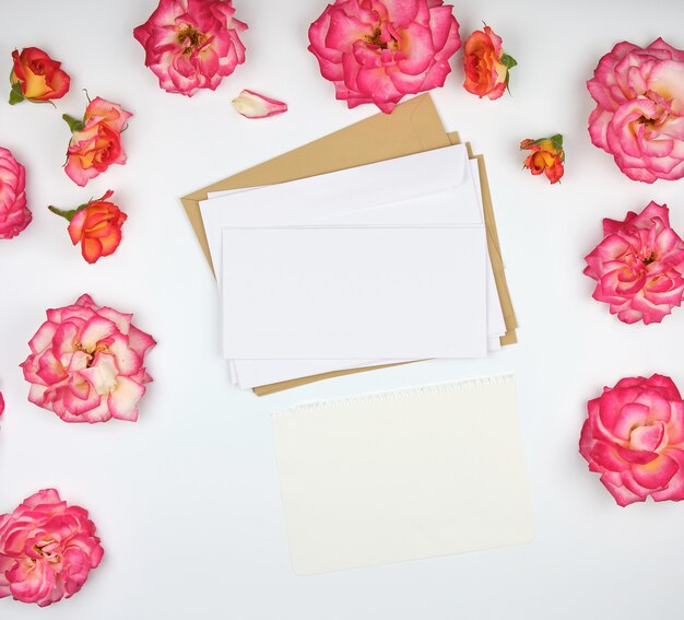 Pink rose buds and a white paper envelope 