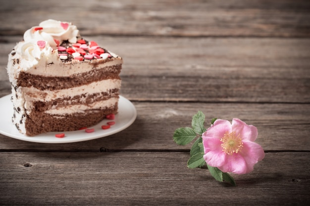 Pink rose and cake on wooden background