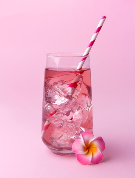 Pink rose cocktail on a pink table with striped pink straw.