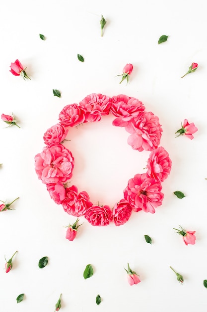 丸い花輪フレームと白い表面にピンクのバラの花のつぼみのパターン