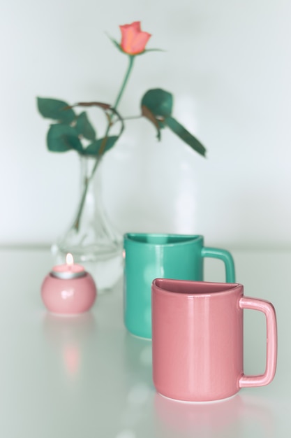 Pink rose flower and twin half tea mugs in salmon pink and fresh mint green.