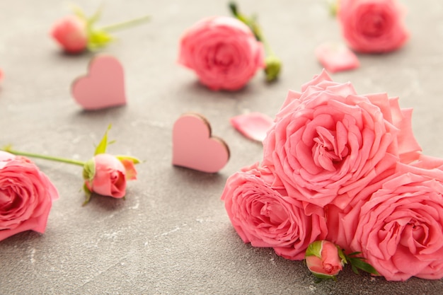 Pink rose flower with hearts on grey background. Spring concept. Top view