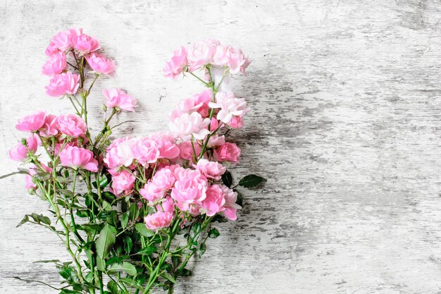 白い素朴な木製の背景にピンクのバラの花の花束