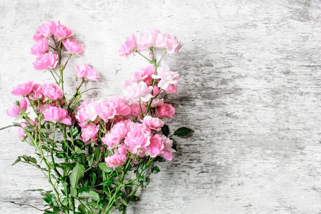 Pink rose flowers bouquet on white rustic wooden background