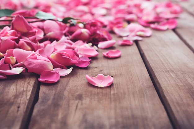 Photo pink rose flowers scattered on wooden table