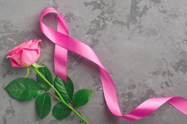 Pink rose and ribbon on concrete background. concept