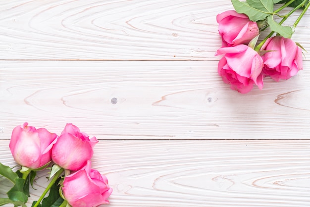 Pink rose in vase on wood background