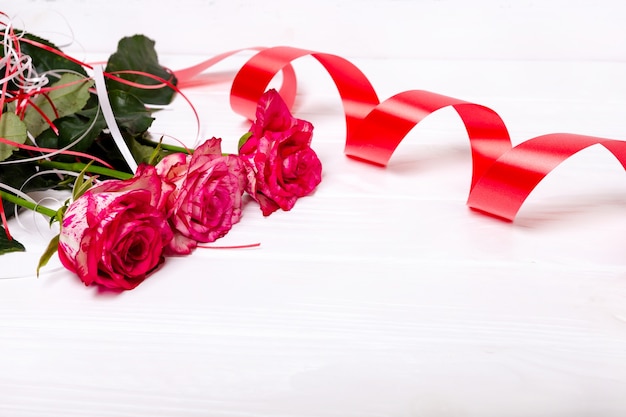 Розовые розы и красная лента, изолированные на белом фоне