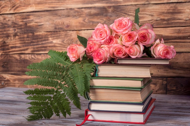 Photo pink roses and books on the wooden background