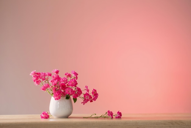 Pink roses in ceramic vase on light red background
