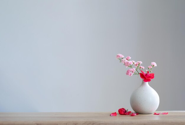 pink roses in ceramic vase on wooden table