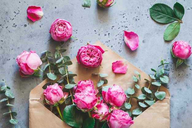 Pink roses in the envelope on a grey background The concept of greetings and celebration Soft focus