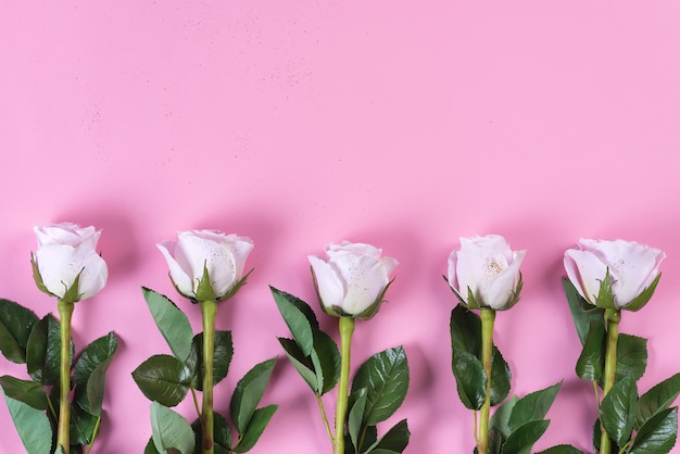 Pink roses flowers with gold glitter on a pink background, flat lay