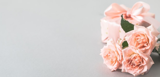 Pink roses and gift box on a gray