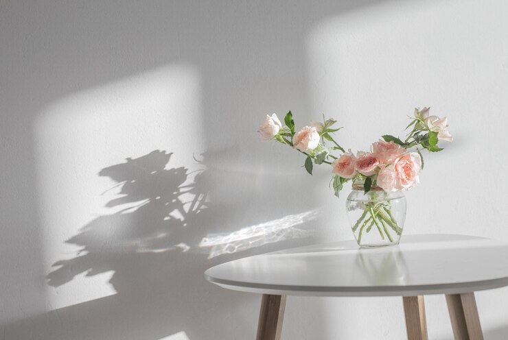 Pink roses in glass jar on white modern table on background white wall