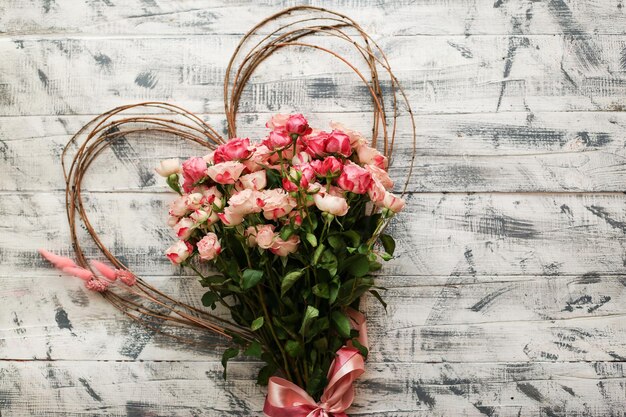 Pink roses in a heart shape on a wooden table