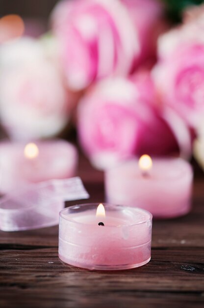 Pink roses and pinl candles on the wooden table