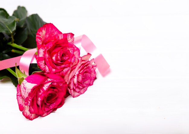 ピンクのバラと白い背景で隔離の赤いリボン