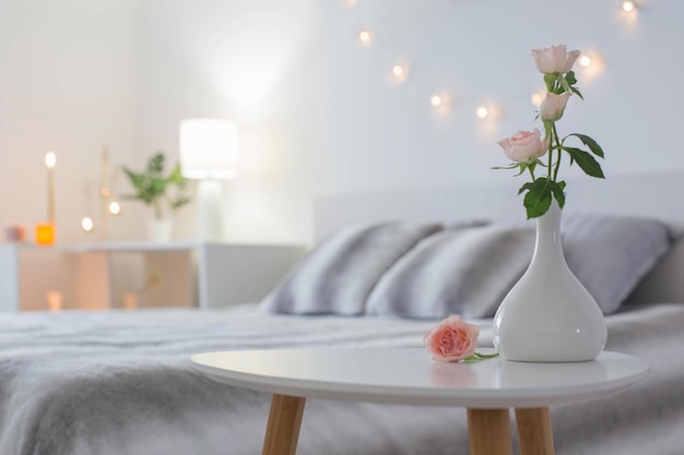 Pink roses in vase on table in bedroom