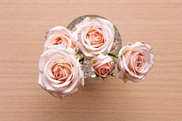 Pink roses in a vase on a wooden desk