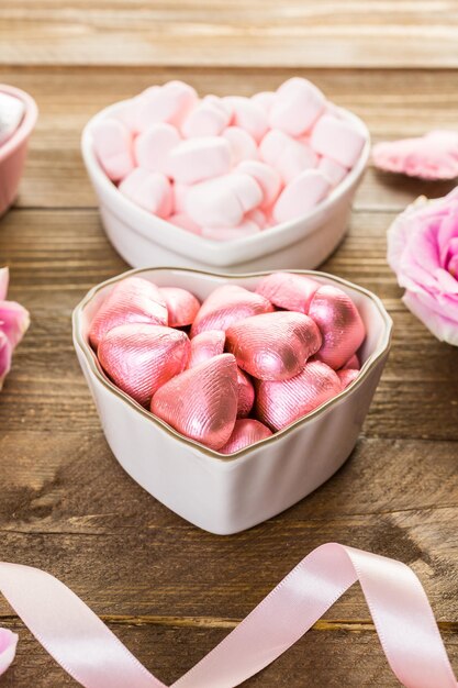 Pink roses with chocolates on rustic wood table.