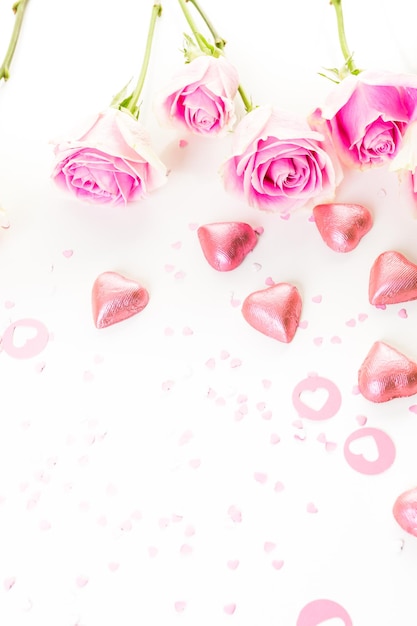 Pink roses with chocolates on a white background.