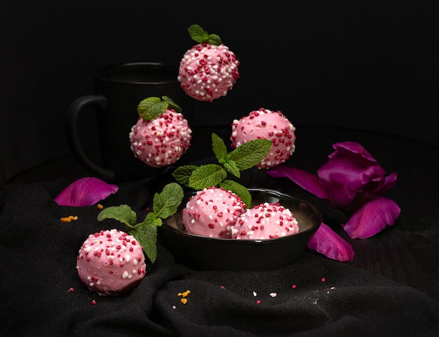 Pink round cupcakes with cookies sprinkled with icing on a black surface with reflection