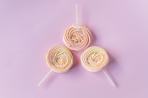 Pink round sweet meringues with decor lie on a pink background