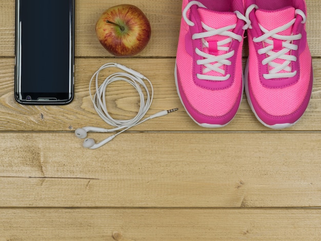 Розовые кроссовки для занятий фитнесом в тренажерном зале и Apple на деревянном полу. Вид сверху.