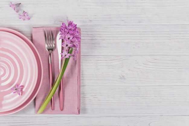 Розовая деревенская обстановка с фиолетовым цветком гиацинта и льняной салфеткой на белой деревянной поверхности