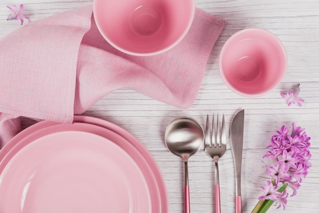 Pink rustic table setting with purple hyacinth flower and linen napkin on white wooden table