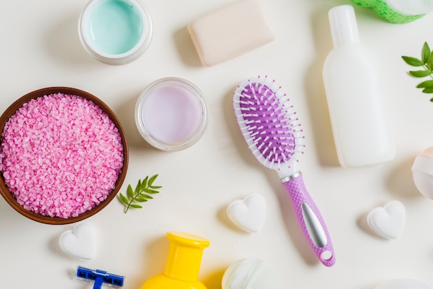 Pink salt; toothbrush and cosmetics products on white backdrop