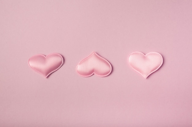 Pink satin hearts on a pink background