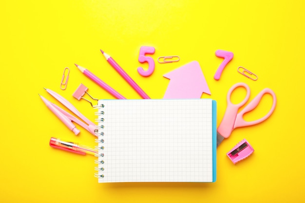 Pink school supplies with notebook on yellow background. Back to school. Flat lay. Top view