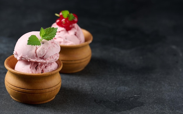 黒いテーブルの上の赤いスグリとアイスキャンディーのピンクのスクープアイスクリーム