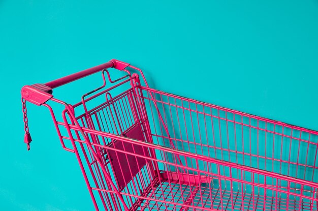 Photo pink shopping cart against colored background