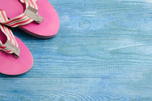 Pink slippers on a blue wooden background summer background and holiday concept