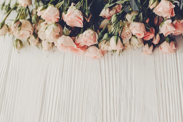 Foto roselline rosa su fondo in legno spazio per testo mockup biglietto di auguri floreale invito a nozzefelice festa della mamma o concetto di san valentino tono vintage bordo tenero fiore