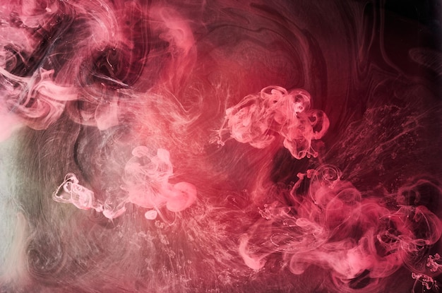 Розовый дым на фоне черных чернил, красочный туман, абстрактное кружащееся прикосновение океанского моря, пигмент акриловой краски под водой