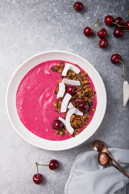 Pink Smoothie from Banana and cherry  Granola and Coconut Shreds on top. Healthy summer breakfast, top view