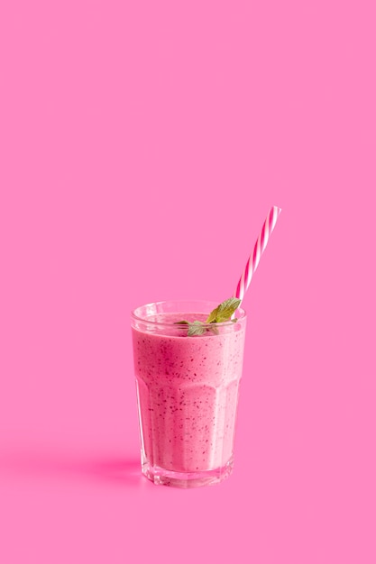 Photo pink smoothie in glass with straw and copy-space