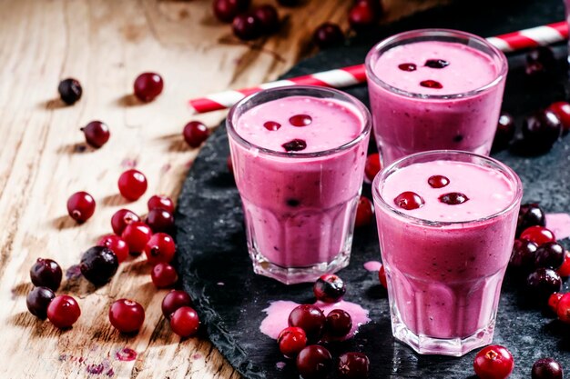 Pink smoothies with milk black currants and cranberries fresh berries on a dark background selective focus