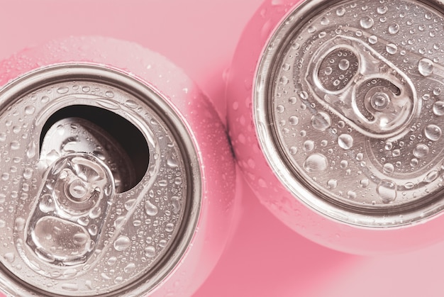 Pink soda cans in water drops top view