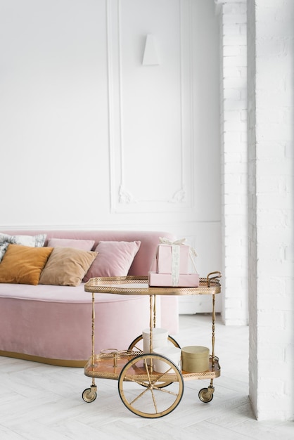 Pink sofa with pillows in a classic white living room and a serving table