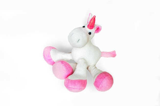 Photo pink soft unicorn toy sitting at white background isolated studio image
