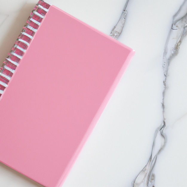 Pink spiral notebook on a white and silver marble countertop