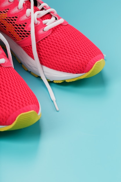 Pink sports sneakers for running on a blue background with free space. Top view, minimalistic concept