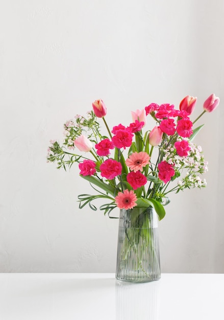 pink spring flowers in glass jug on white background